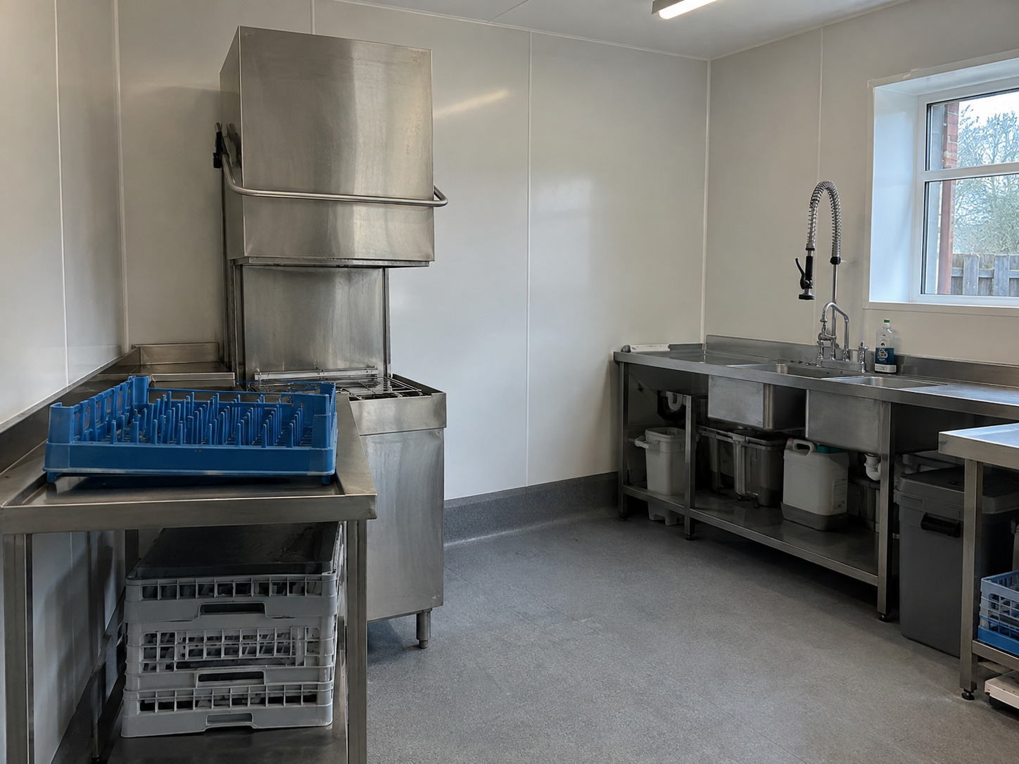 White hygienic PVC wall cladding and coved vinyl flooring in a commercial kitchen wash-up area in Winchester, Hampshire